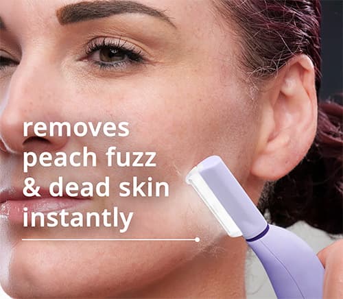 Person using a sonic dermaplaning tool in front of a bathroom mirror